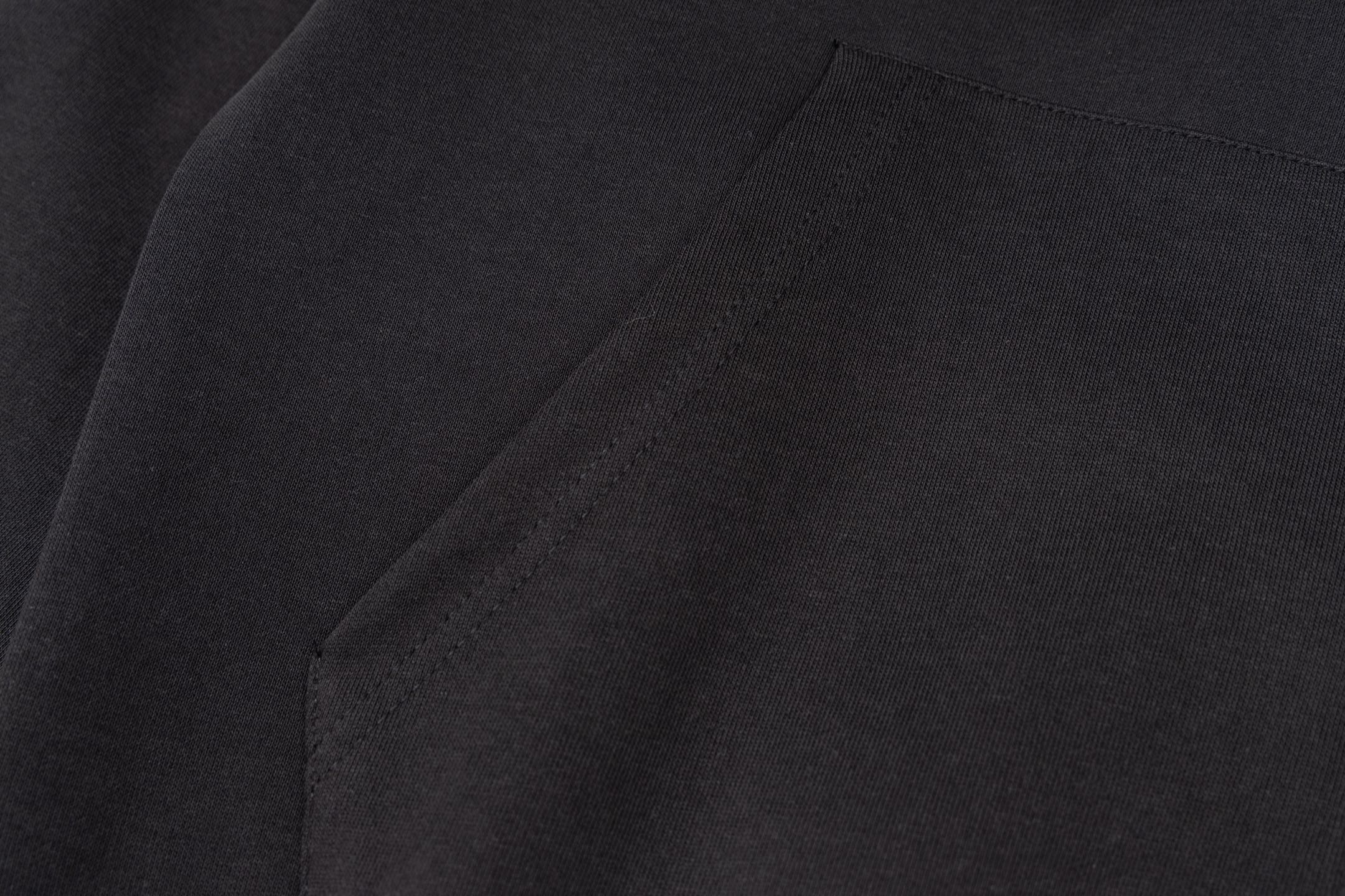 Black jacket fabric with subtle texture and stitched seam line