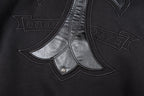 Black zip-up jacket front with chrome-style cross applique and stitched seams