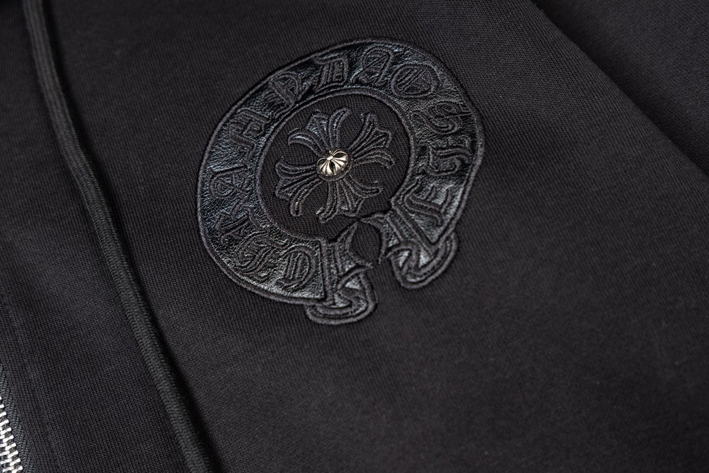 Black hoodie side close-up with embroidered round emblem patch