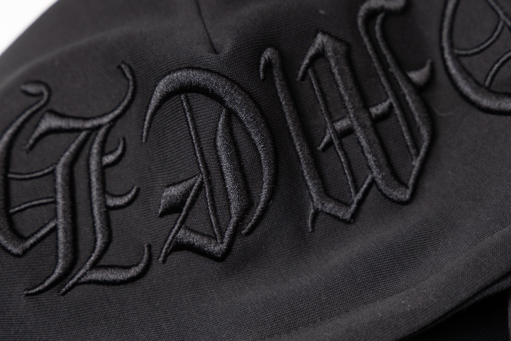 Black hoodie sleeve close-up with embroidered script logo text
