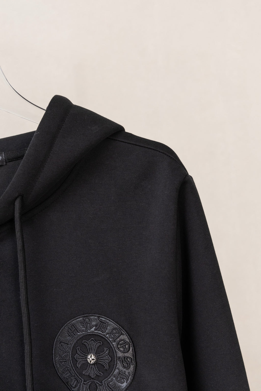 Black zip-up hoodie side view with circular sleeve emblem