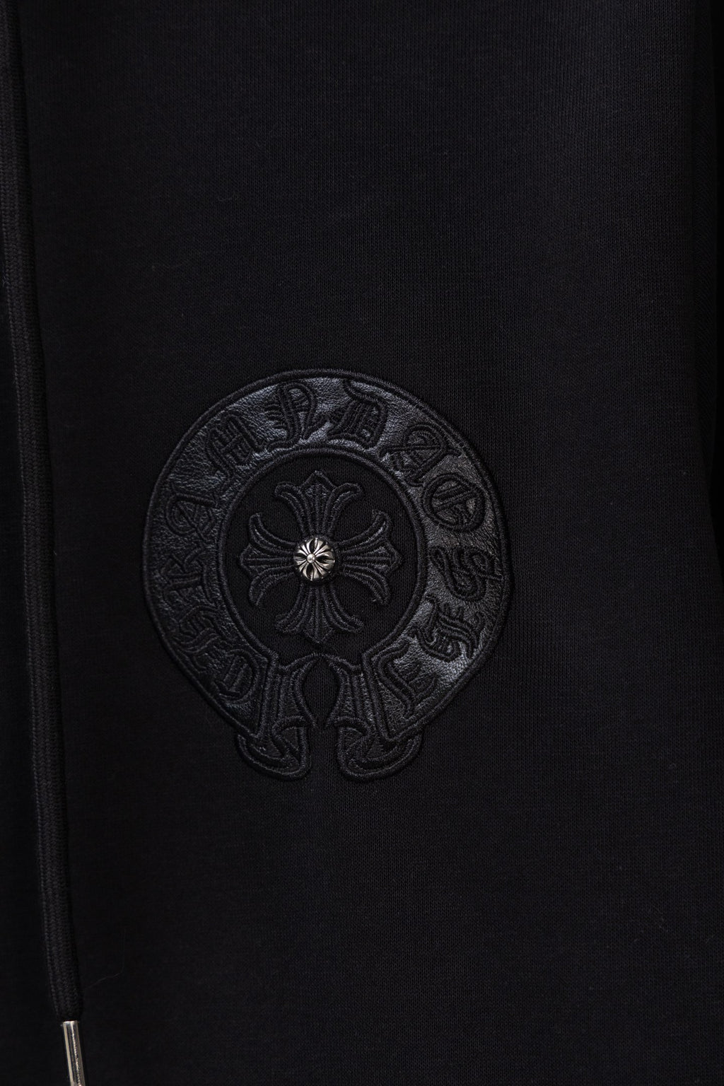 Black zip-up hoodie chest close-up with circular embossed emblem