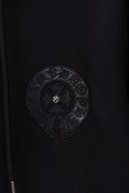 Black zip-up hoodie chest close-up with circular embossed emblem