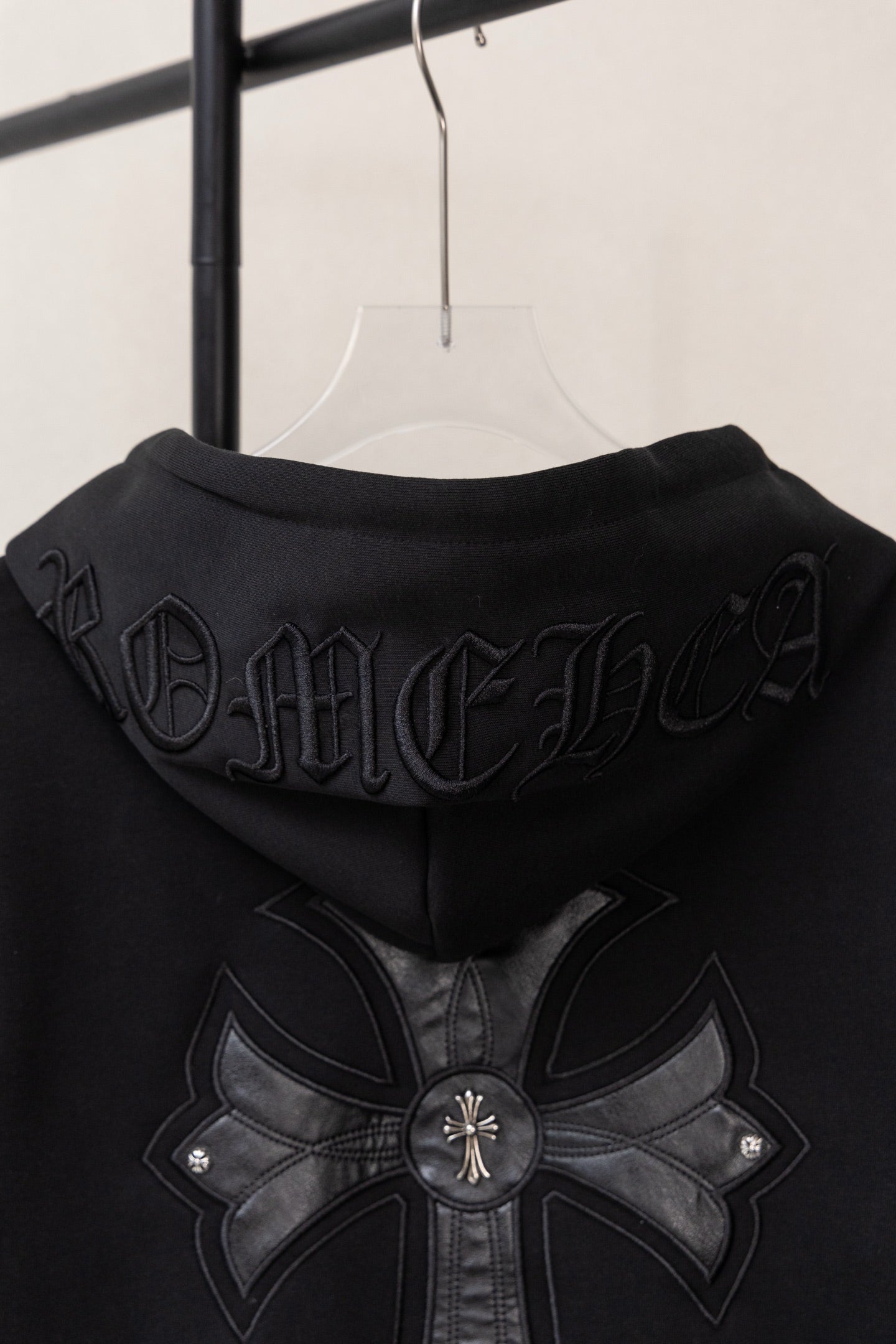 Black zip-up hoodie back view with embossed gothic lettering and large floral cross