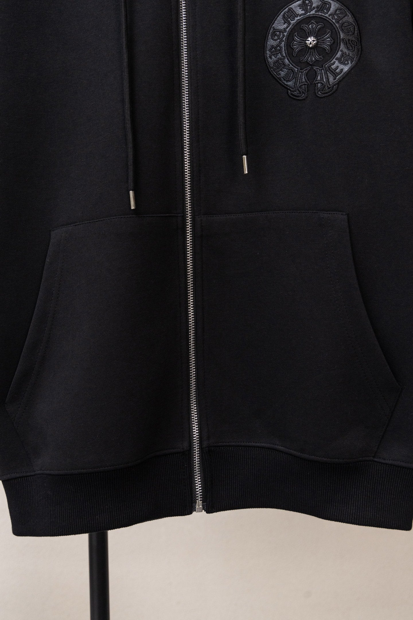 Black zip-up hoodie front close-up with metal zipper and kangaroo pocket