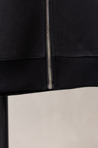 Black zip hoodie close-up: center zipper and ribbed cuffs
