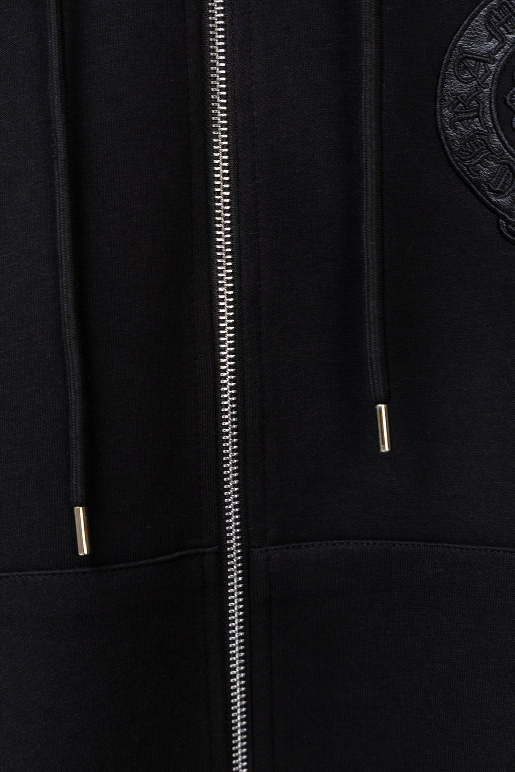 Black zip-up hoodie close-up of metal zipper and hood drawstring tips