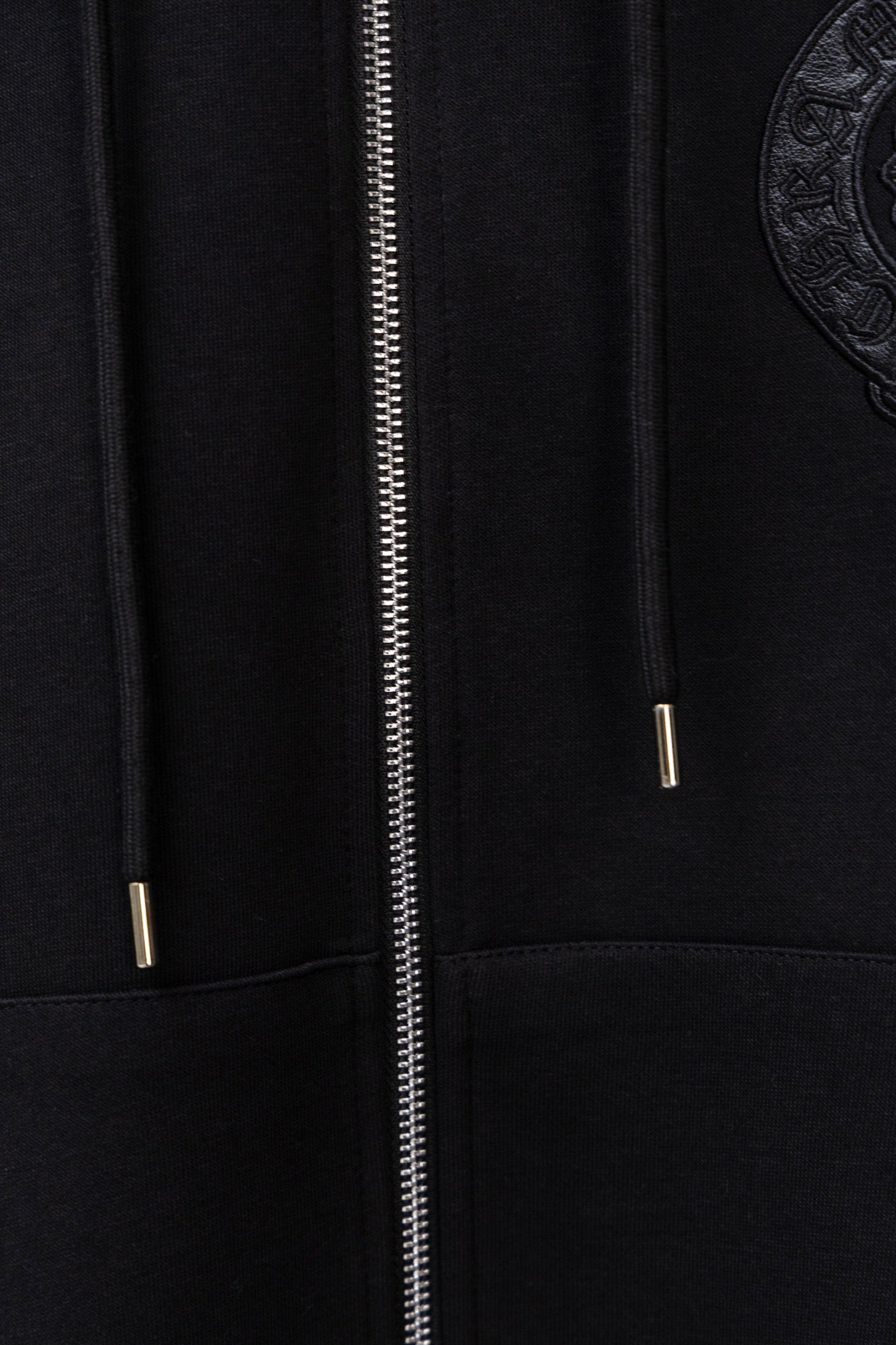 Black zip-up hoodie close-up of metal zipper and hood drawstring tips