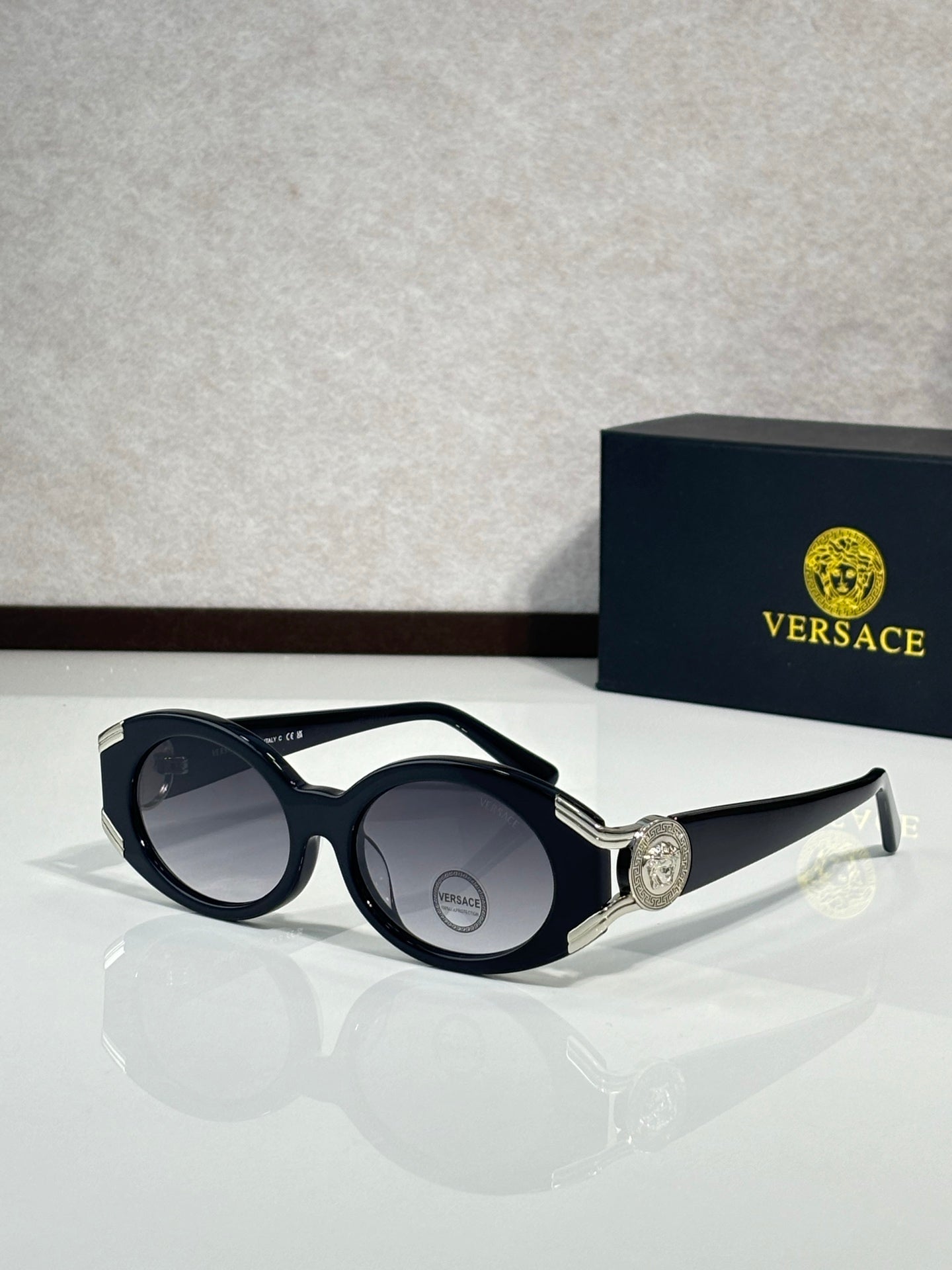 Sunglasses with black round frames, silver side emblem, dark lenses
