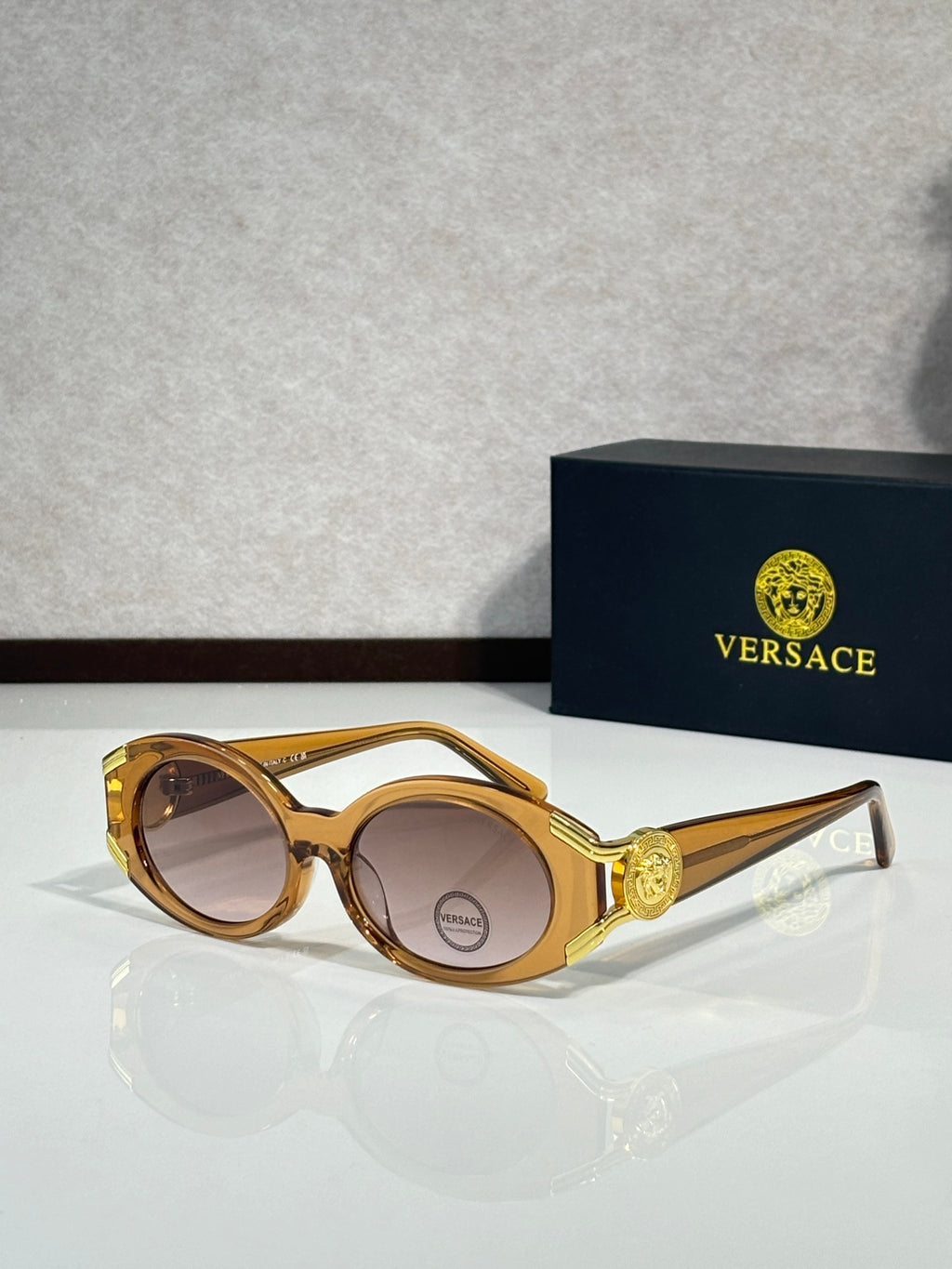 Sunglasses with gold round frames, gold side emblem, warm tinted lenses