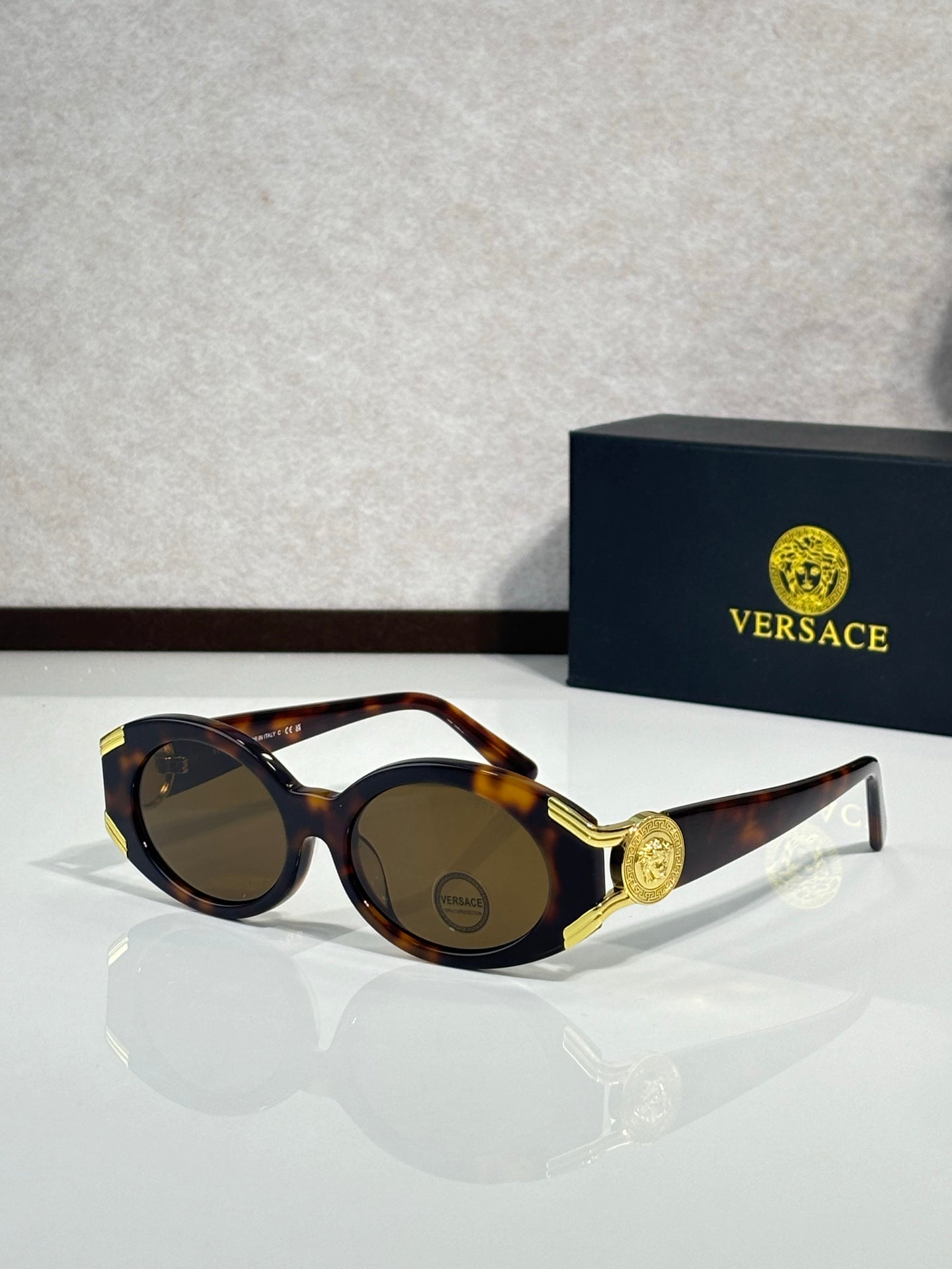 Sunglasses with tortoise round frames, gold side emblem, dark lenses