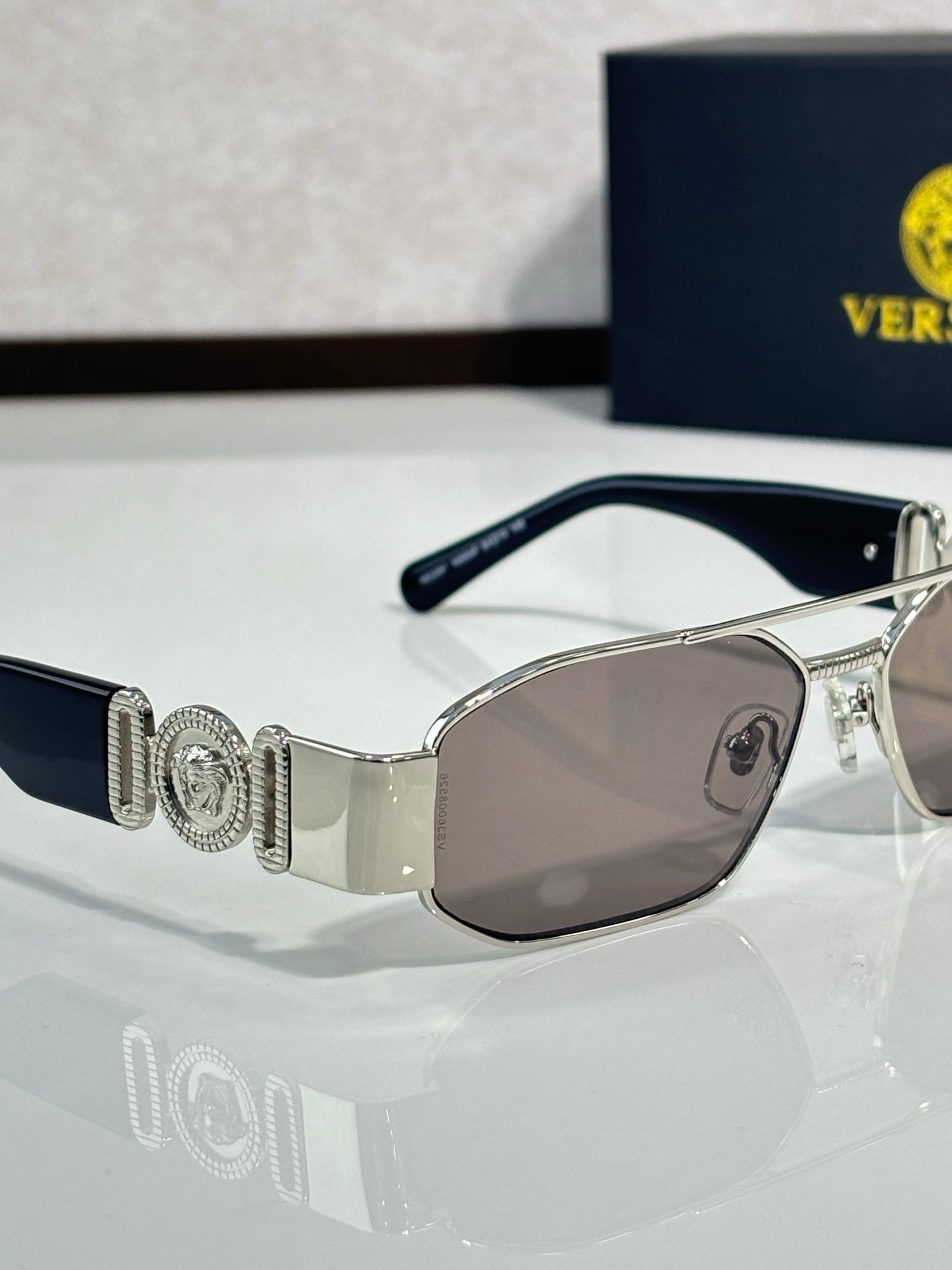 Sunglasses with silver metal frame and light brown tinted lenses, logo detail on temple