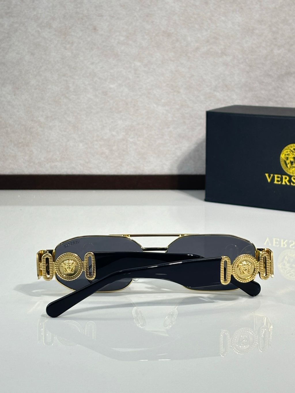 Sunglasses with dark navy frame and gold medallion-style temple accents