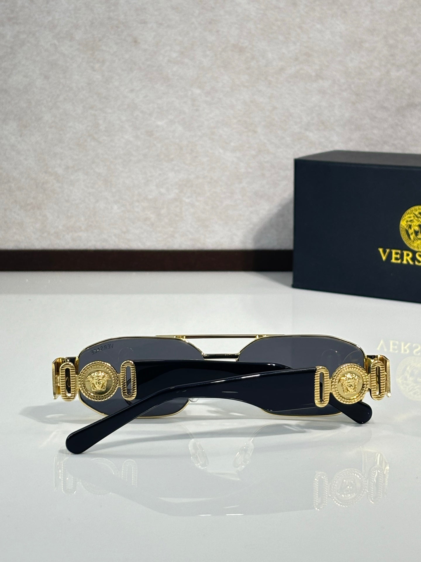 Sunglasses with dark navy frame and gold medallion-style temple accents