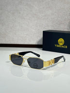 Sunglasses with gold frame and dark lenses, ornate logo detail on temple