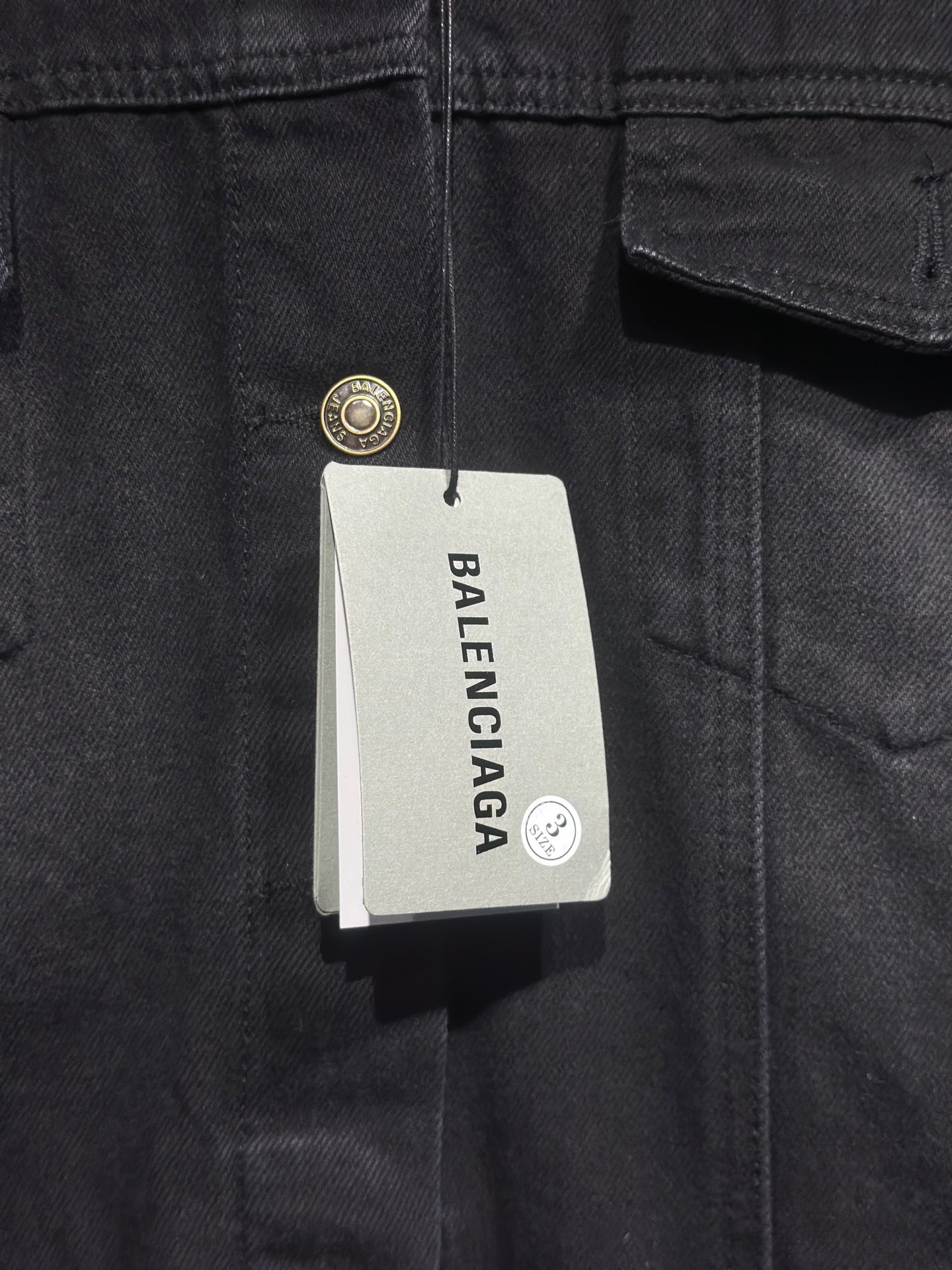 Balenciaga-branded size tag on dark denim hooded jacket