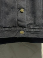 Dark denim jacket cuff with two gold-tone snap buttons