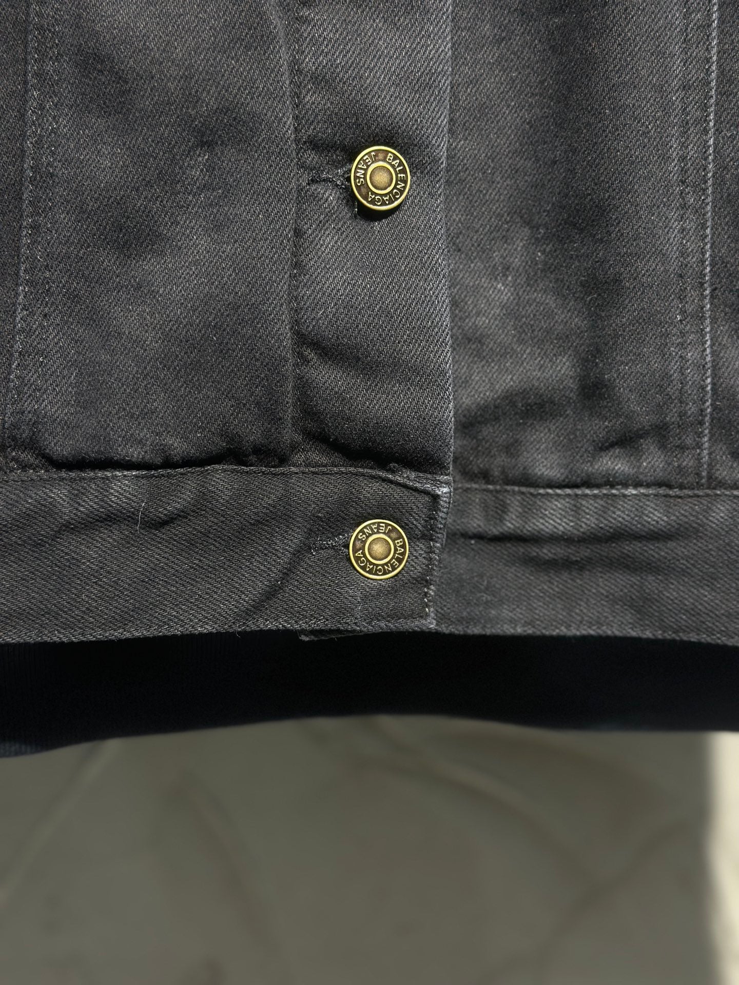 Dark denim jacket cuff with two gold-tone snap buttons