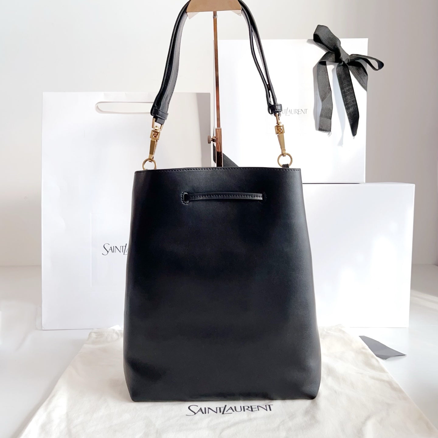 YSL black leather tote-style bag with top handles, gold hardware, and bow detail