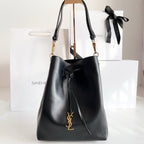YSL black leather bucket bag with drawstring, gold YSL logo, and shoulder straps