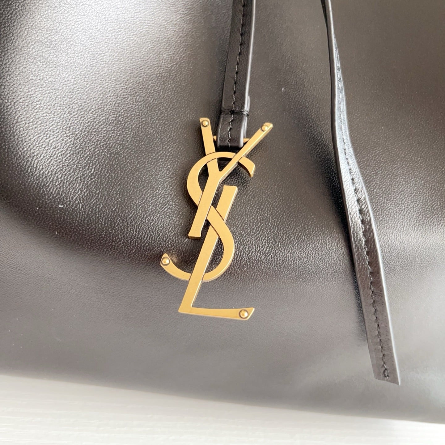 YSL black leather bag with gold YSL logo charm on the front panel
