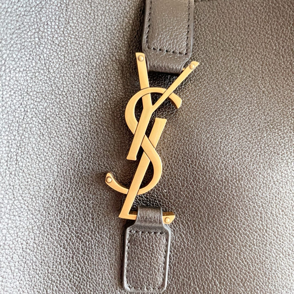 YSL black leather bag close-up of gold YSL logo keychain charm