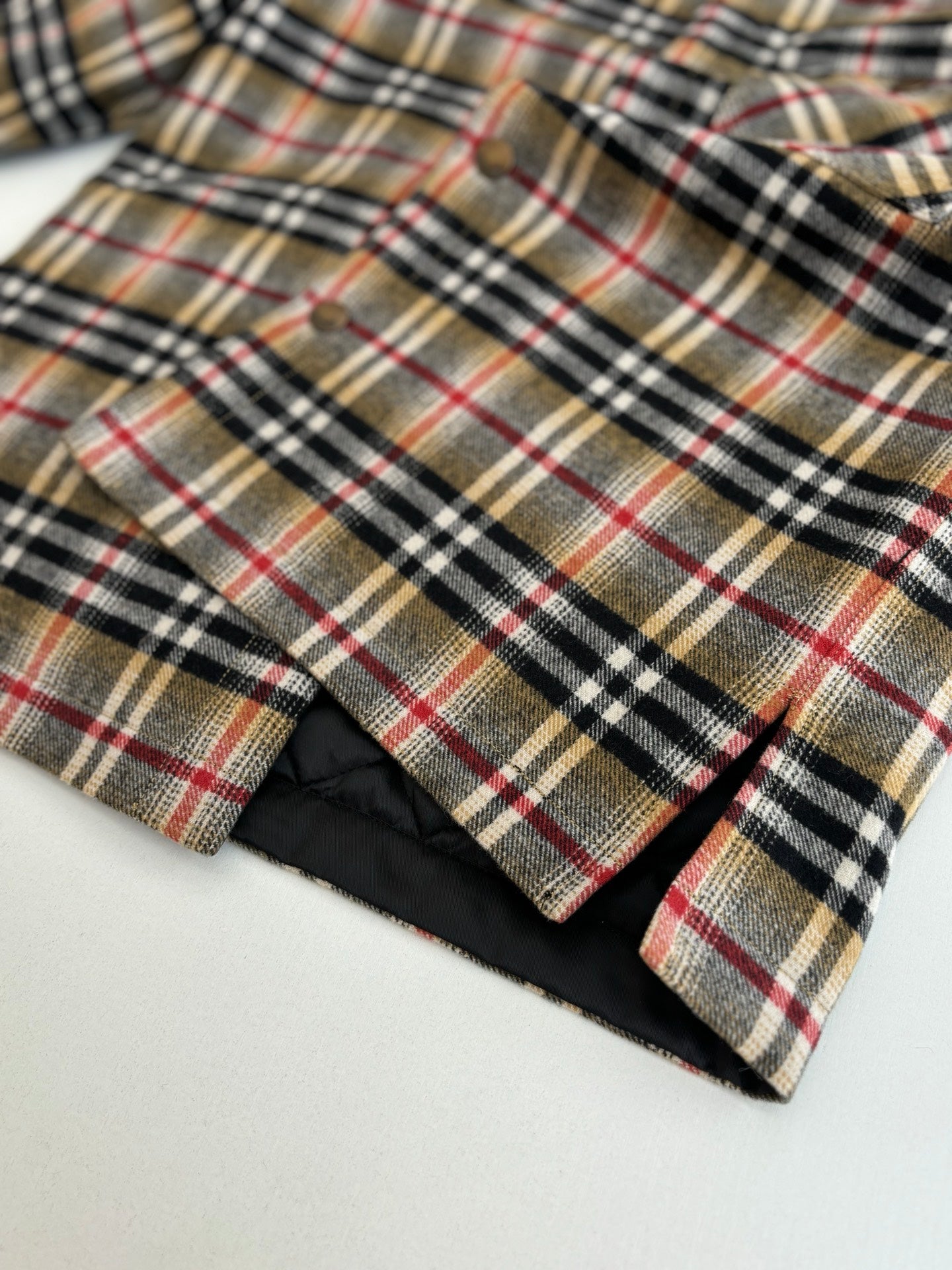 Burberry plaid shirt hem with black underside lining, close-up