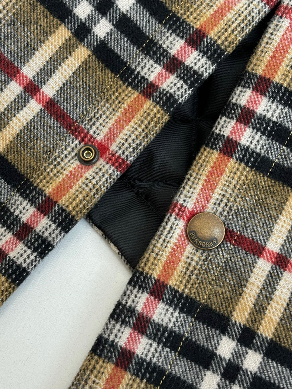 Plaid long-sleeve jacket front with metal snap buttons and black quilted lining