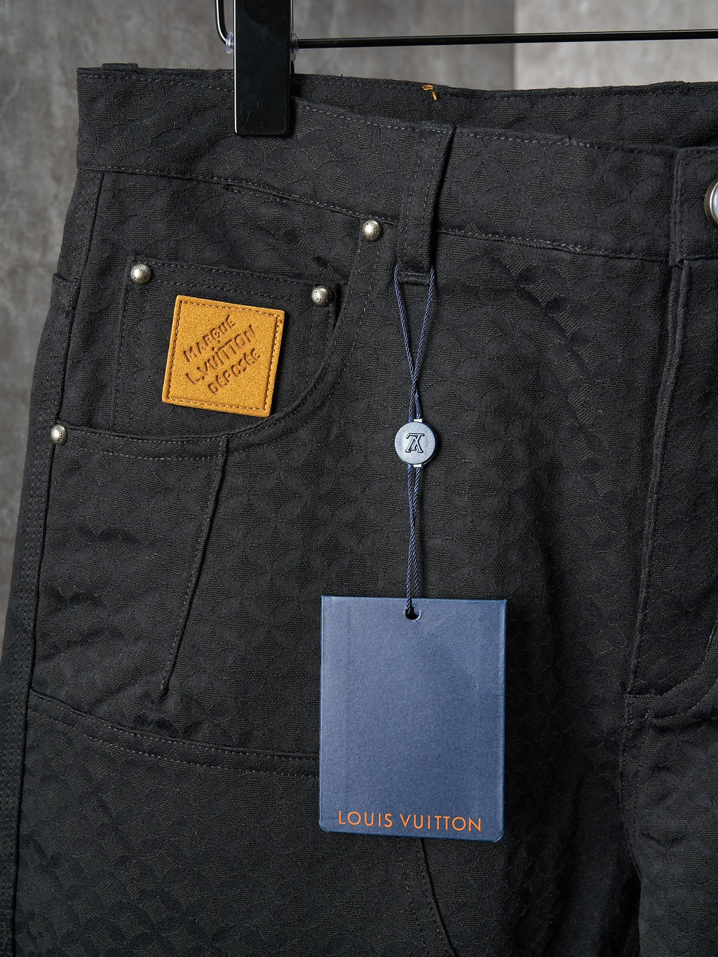 Louis Vuitton pants close-up of front pockets with gold hardware and hanging price tag