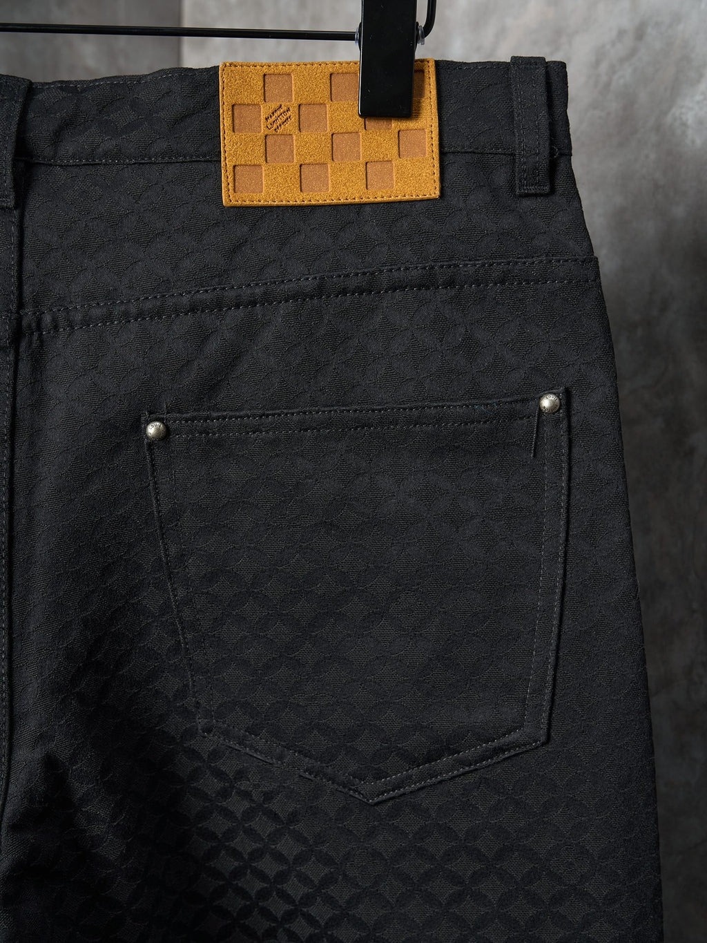 Louis Vuitton pants close-up of back pocket with tan logo patch and gold button hardware