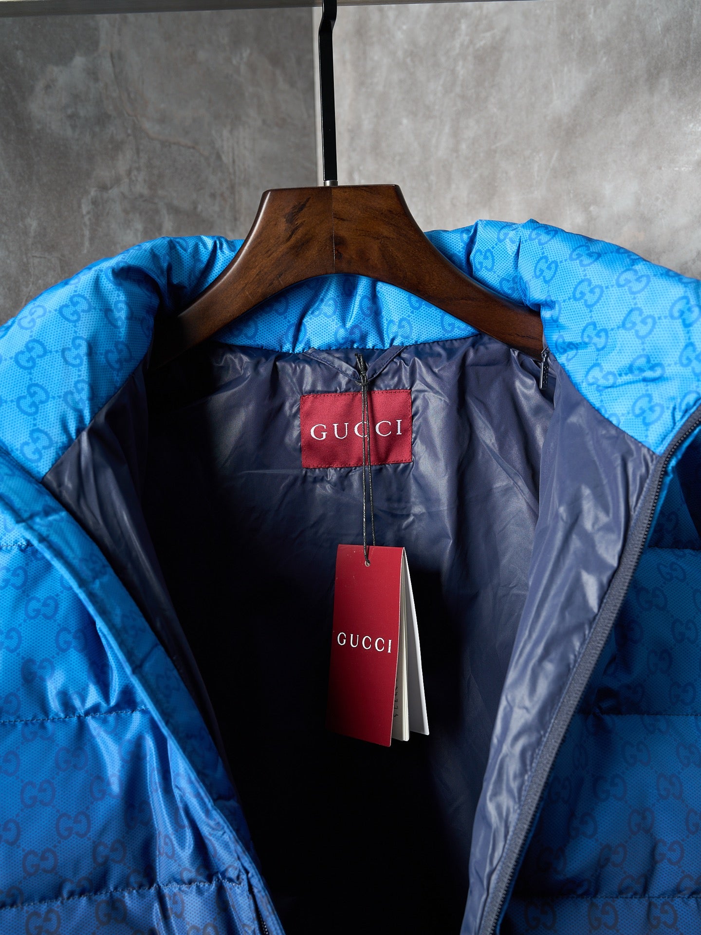 Puffer jacket interior with Gucci label and red hang tag on wooden hanger