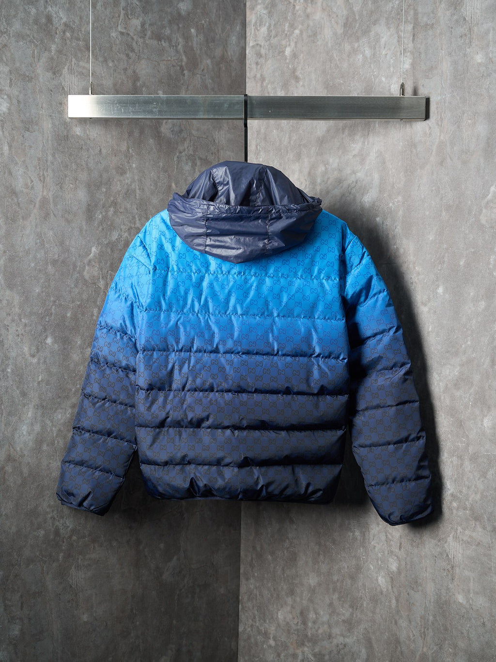 Blue puffer jacket with hood at back and horizontal padded quilting