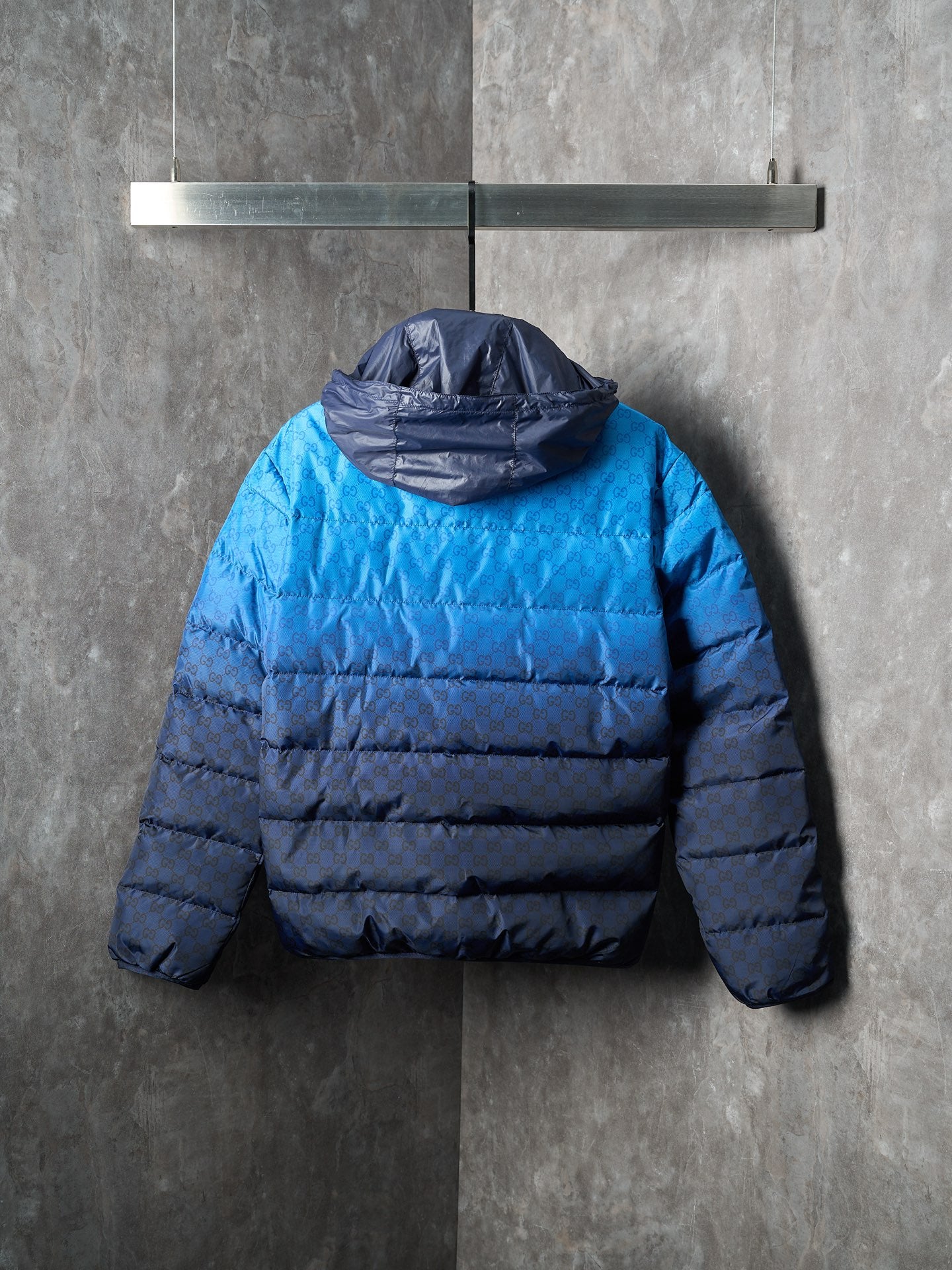 Blue puffer jacket with hood at back and horizontal padded quilting