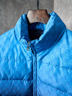 Blue hooded puffer jacket with monogram pattern, front zipper, and metal pull tab