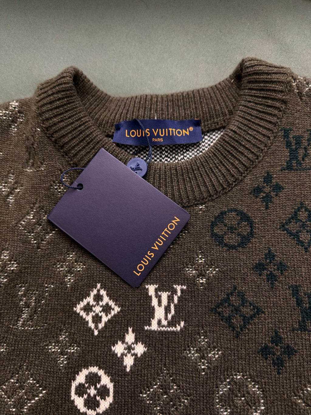Brown knit sweater close-up with Louis Vuitton tag and monogram pattern