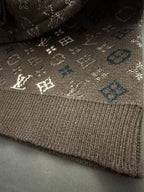 Brown knit sweater hem with ribbed cuff and small white monogram details