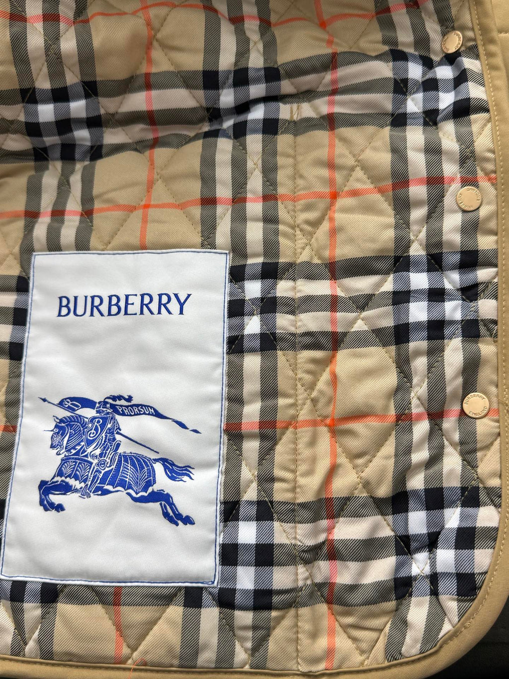Plaid quilted jacket lining with Burberry logo patch and metal snap