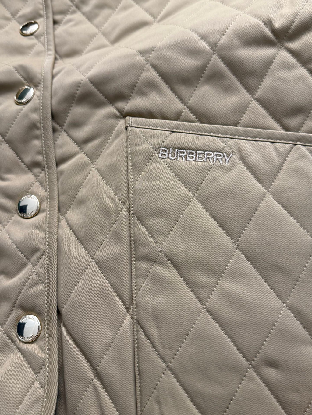 Tan quilted jacket with Burberry logo patch on chest and snap buttons