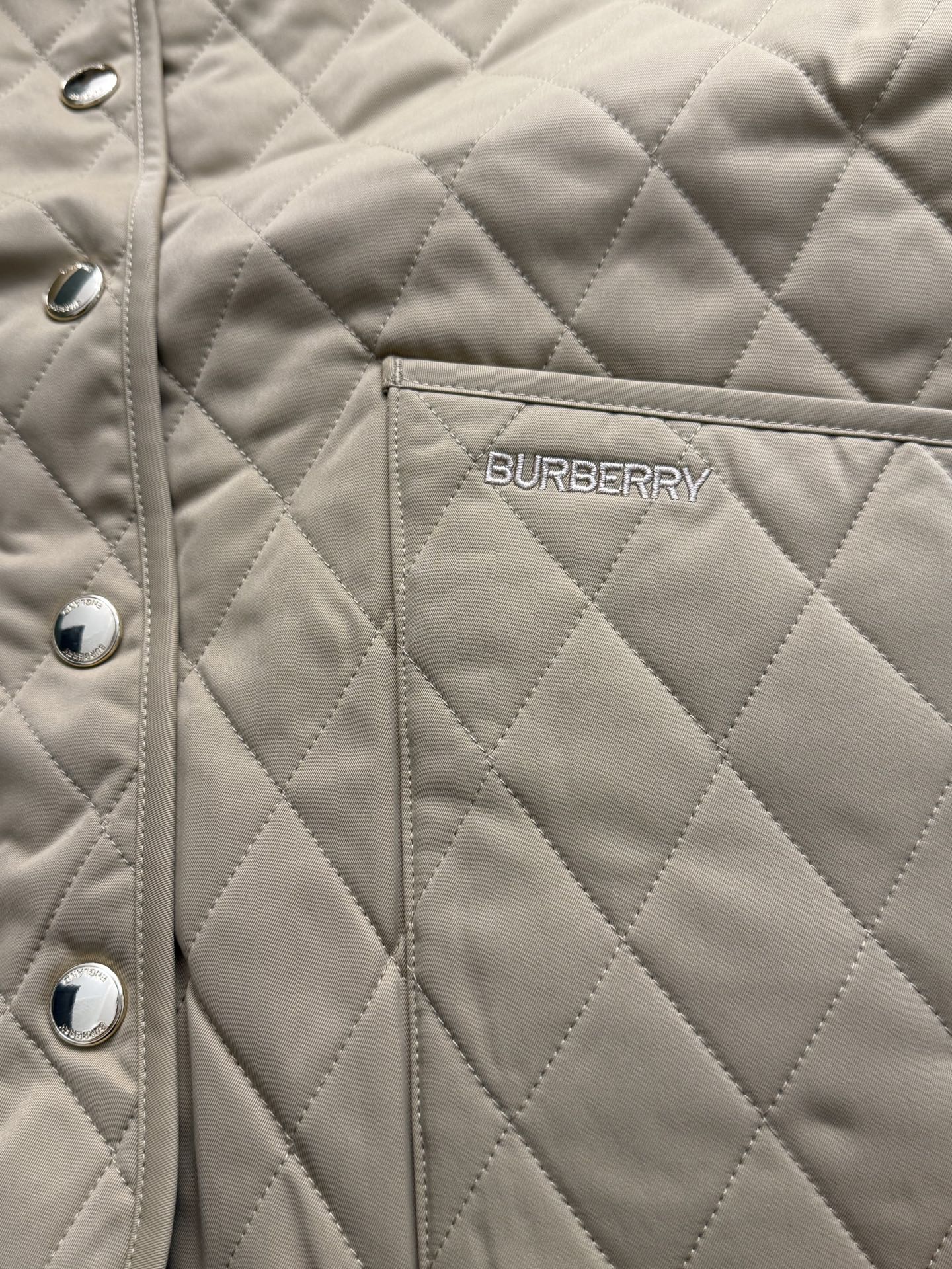Tan quilted jacket with Burberry logo patch on chest and snap buttons