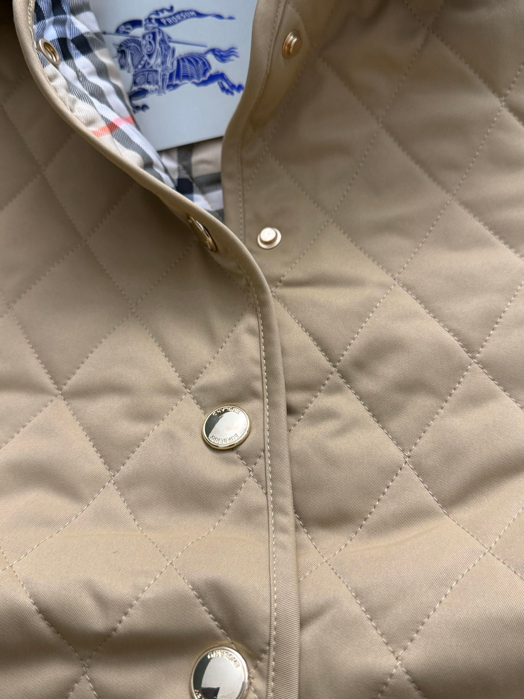 Quilted tan jacket front with snap buttons and round metal details
