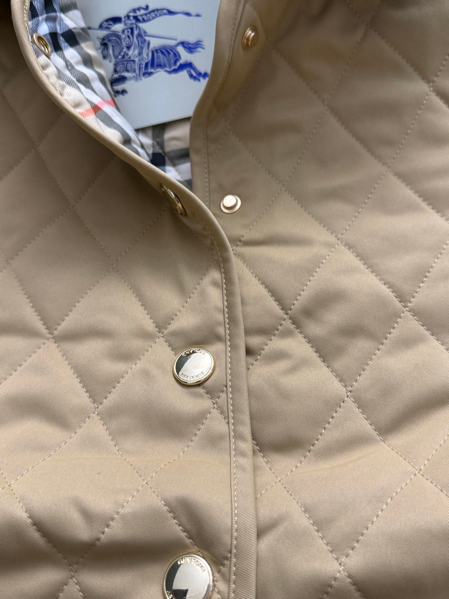 Quilted tan jacket front with snap buttons and round metal details