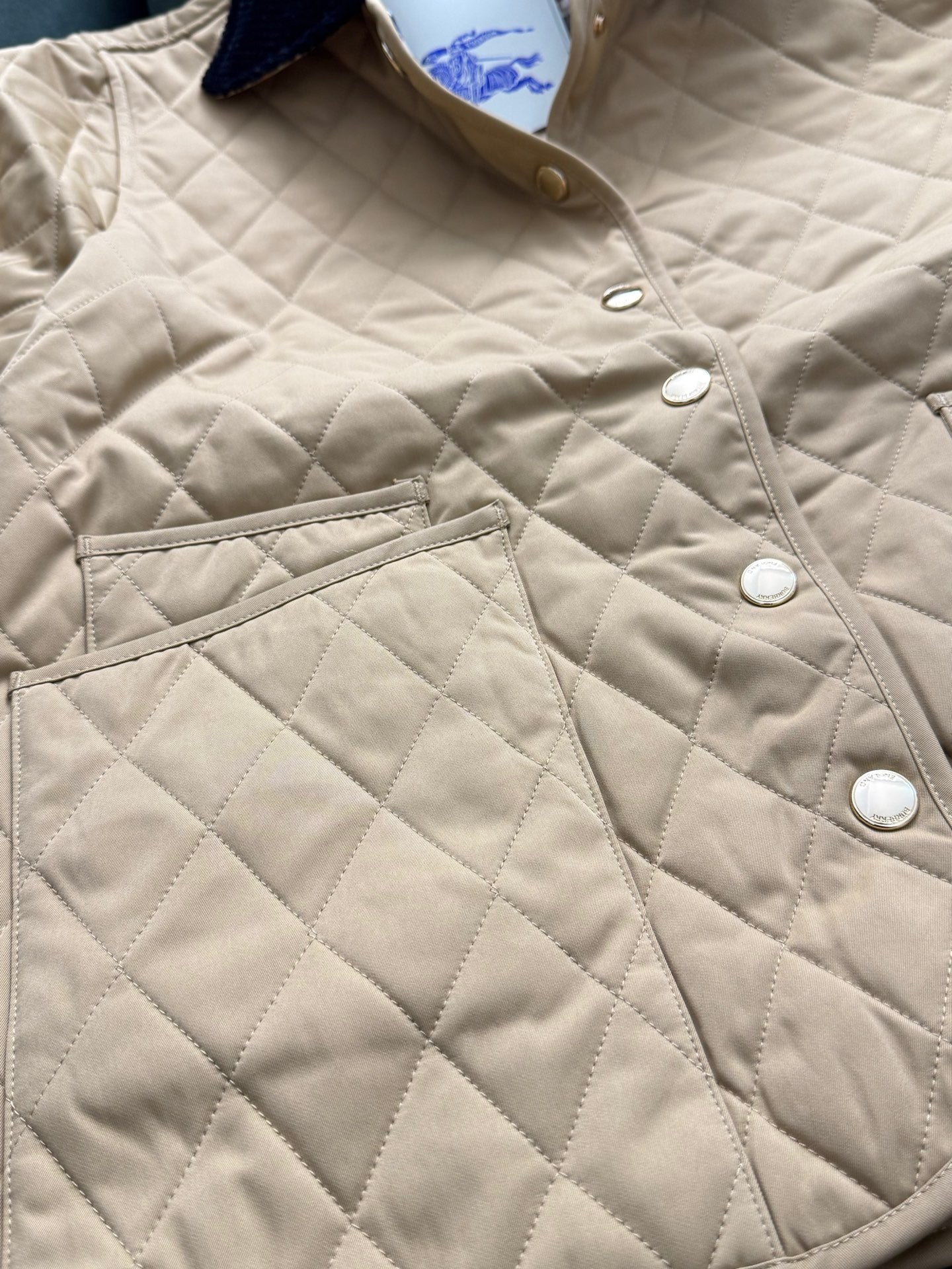 Tan quilted jacket with button placket, pointed collar, and front flap pocket