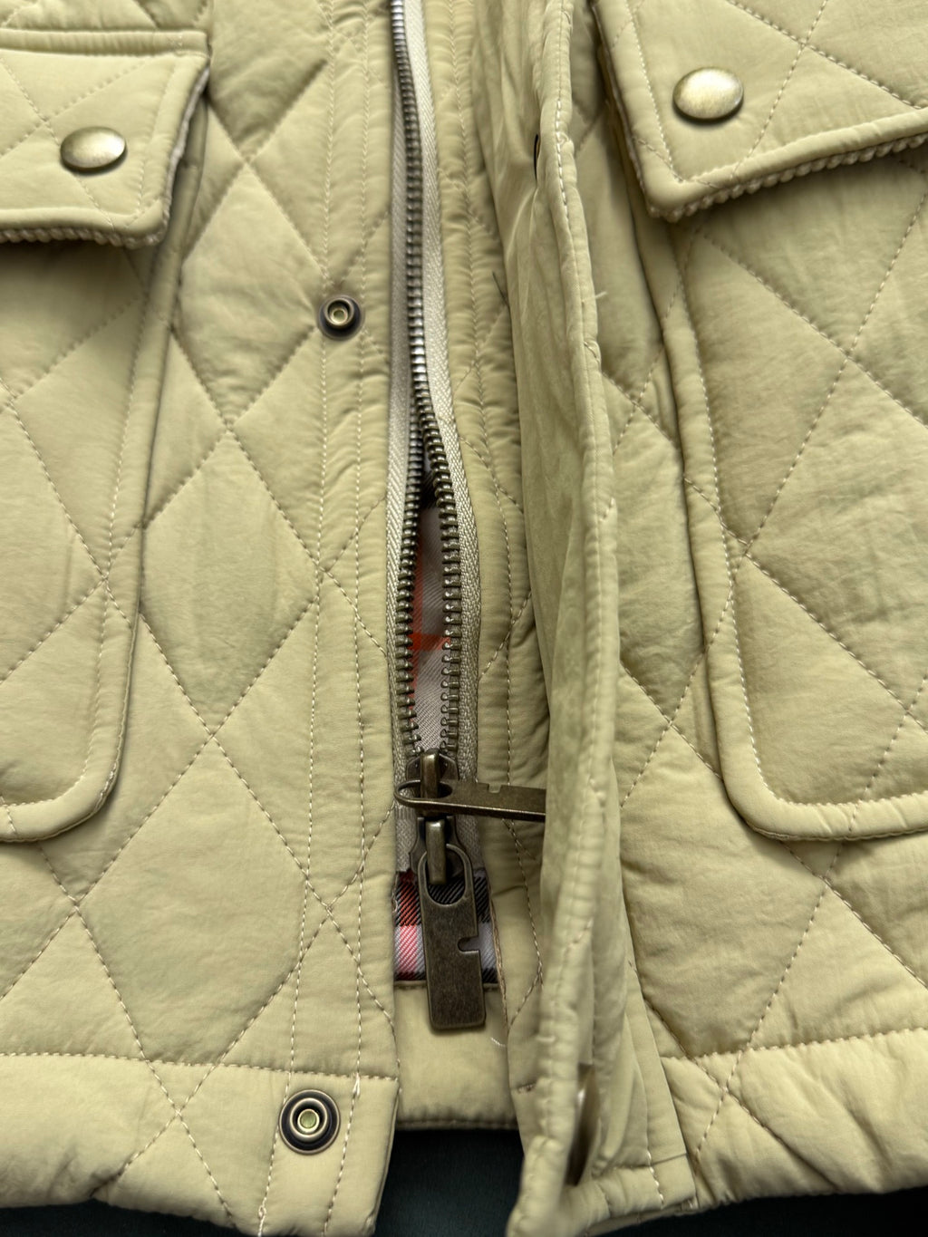 Light yellow quilted jacket showing front zipper and metal pull