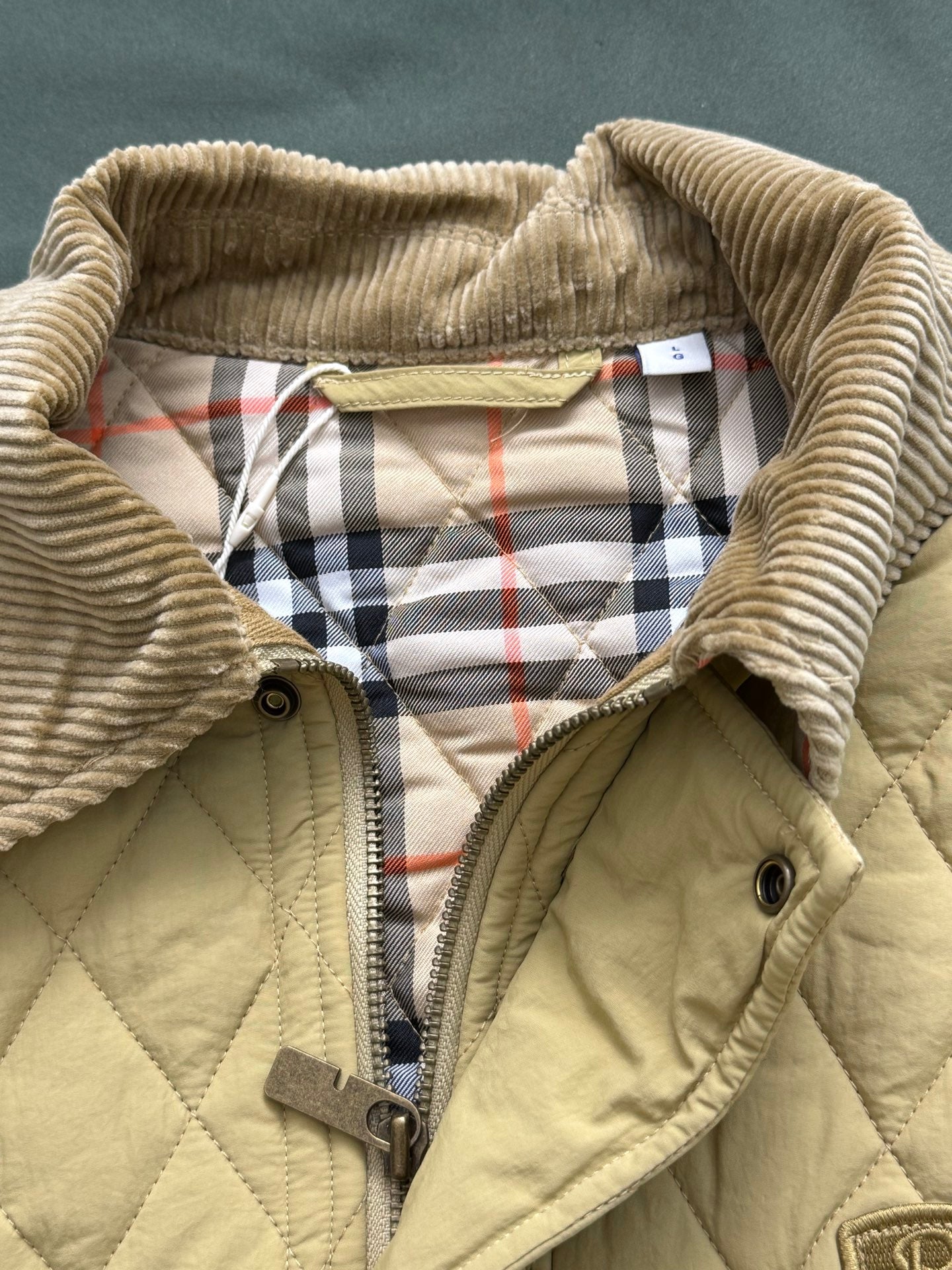 Light yellow quilted jacket lining with plaid hood trim and zipper