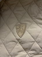 Embroidered shield logo patch on light yellow quilted jacket