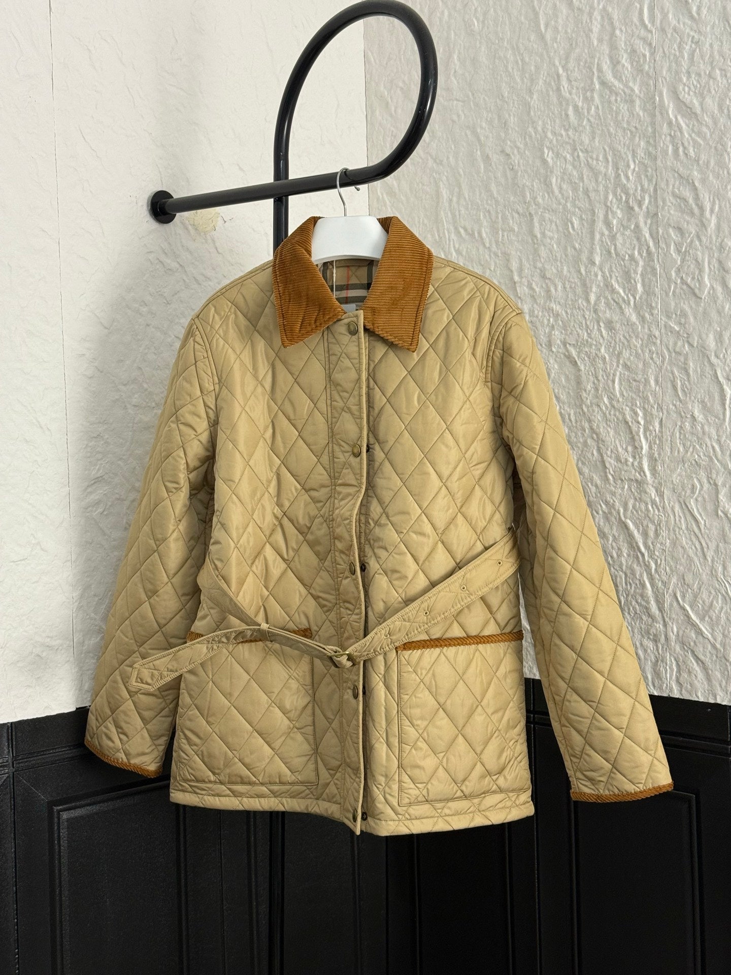 Quilted jacket with corduroy collar, front zipper, and tan drawcord tie at waist