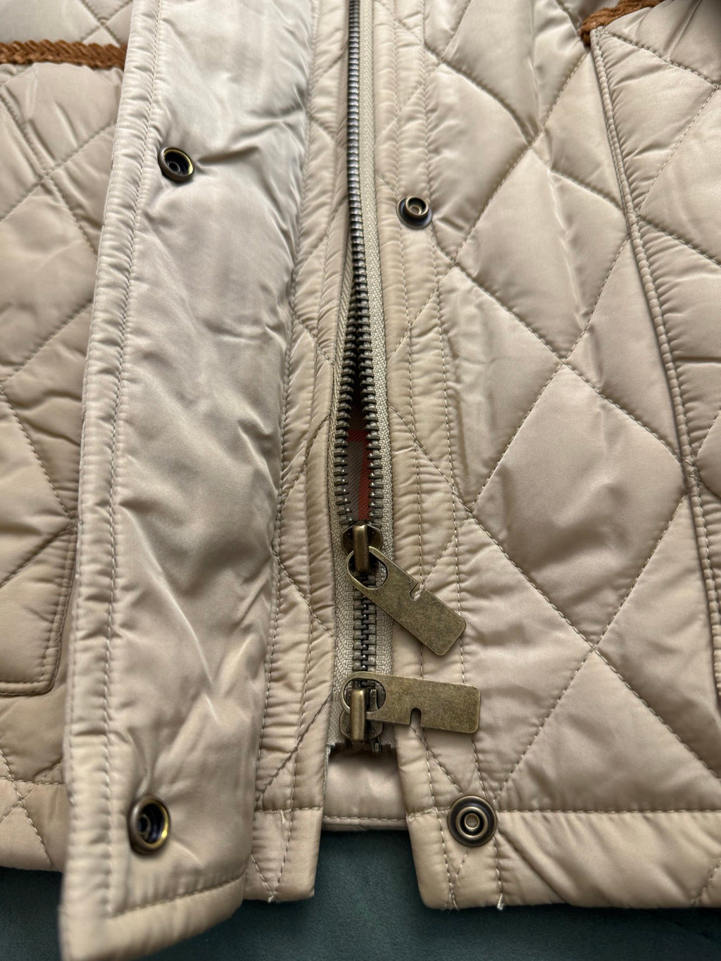 Quilted jacket front with zipper, snap buttons, and metal ring hardware