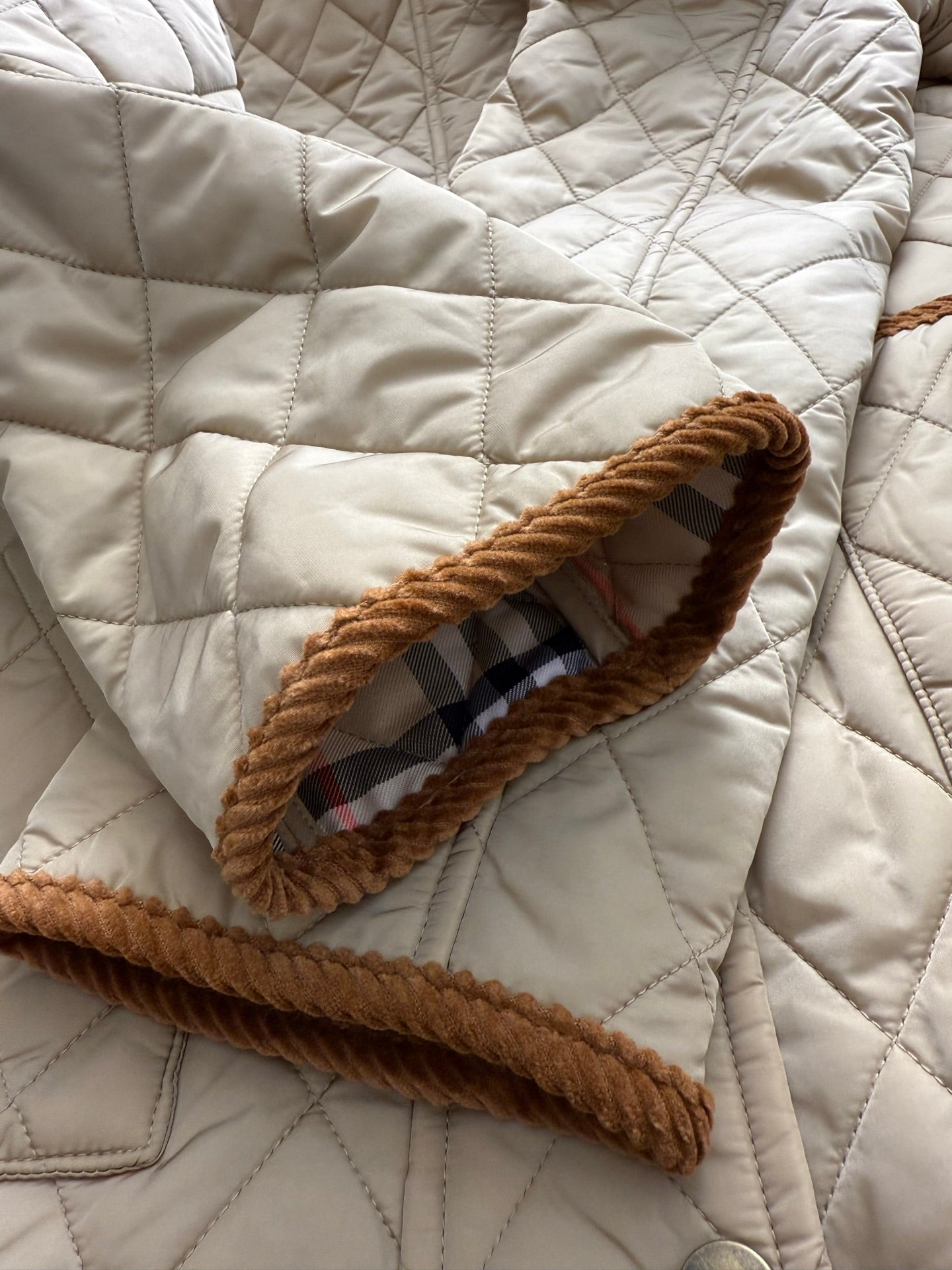 Quilted jacket pocket with plaid inner trim and tan braided edge cord border