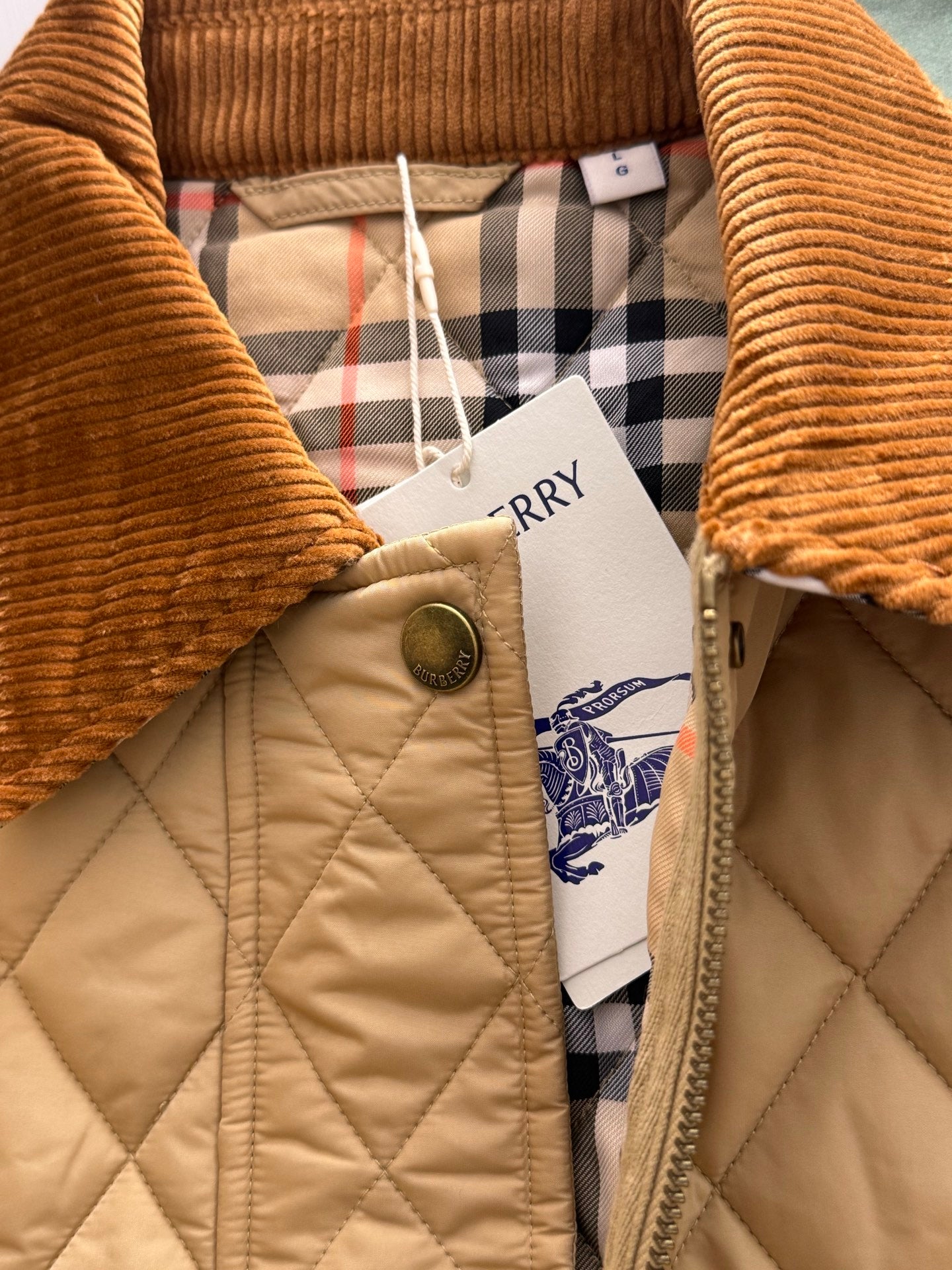 Quilted jacket with corduroy collar, plaid lining, snap button, and attached price tag