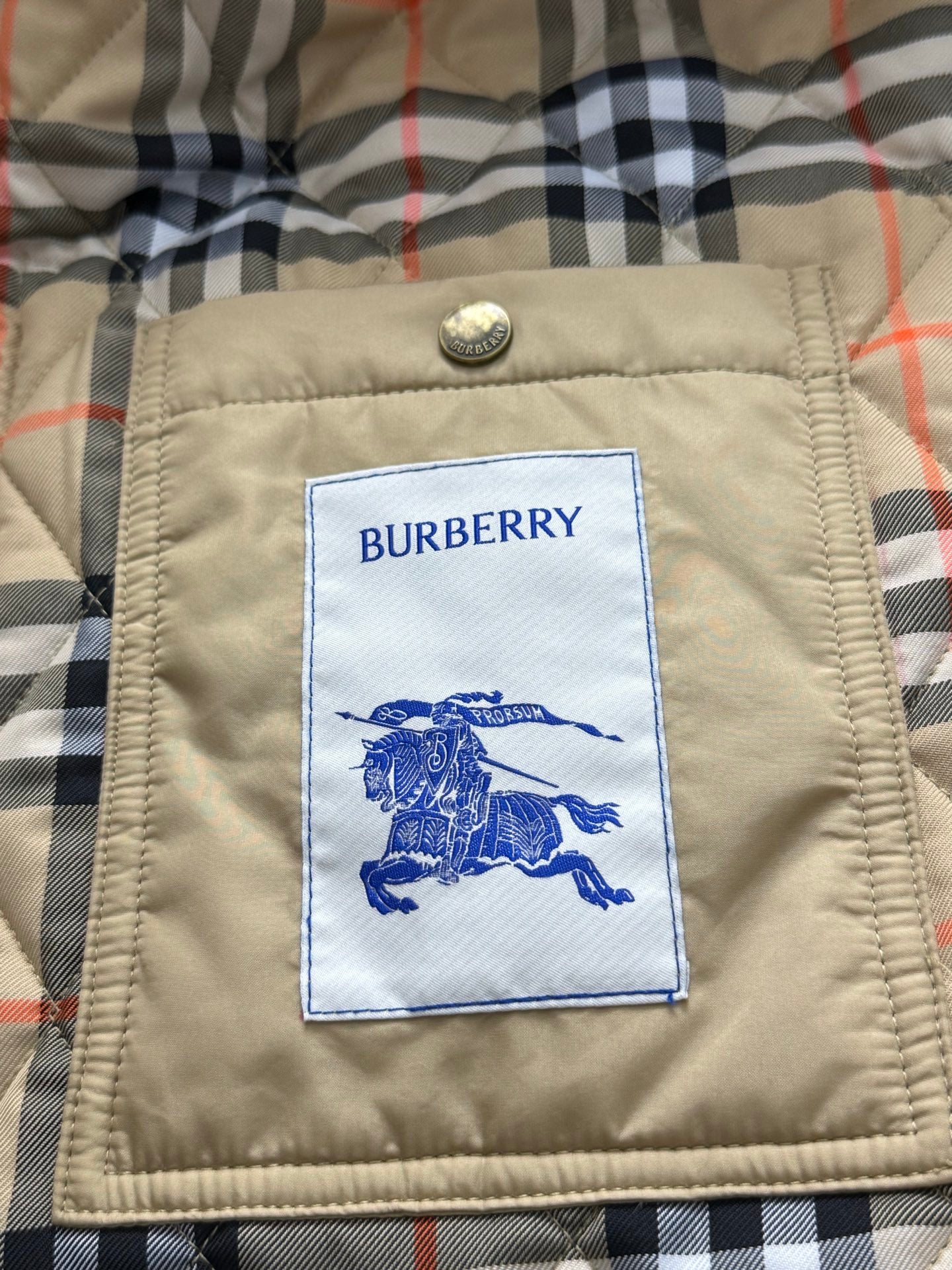 Burberry brand label patch on quilted jacket lining, with blue horse logo